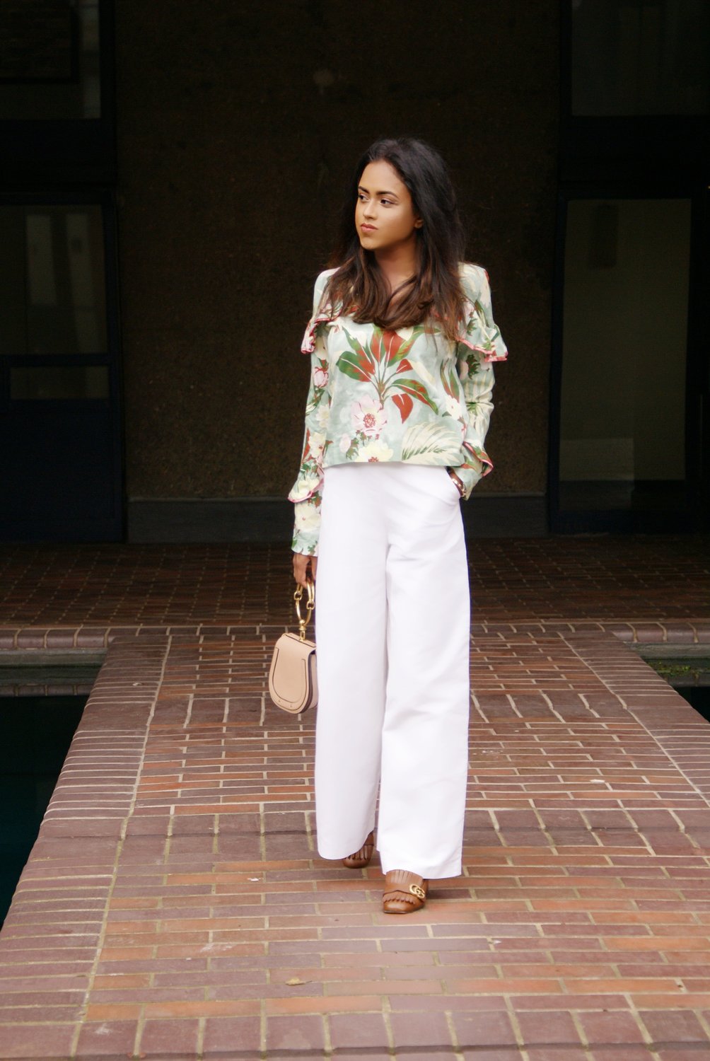 Sachini wearing a floral top and brown Gucci shoes holding a pink Chloé bag