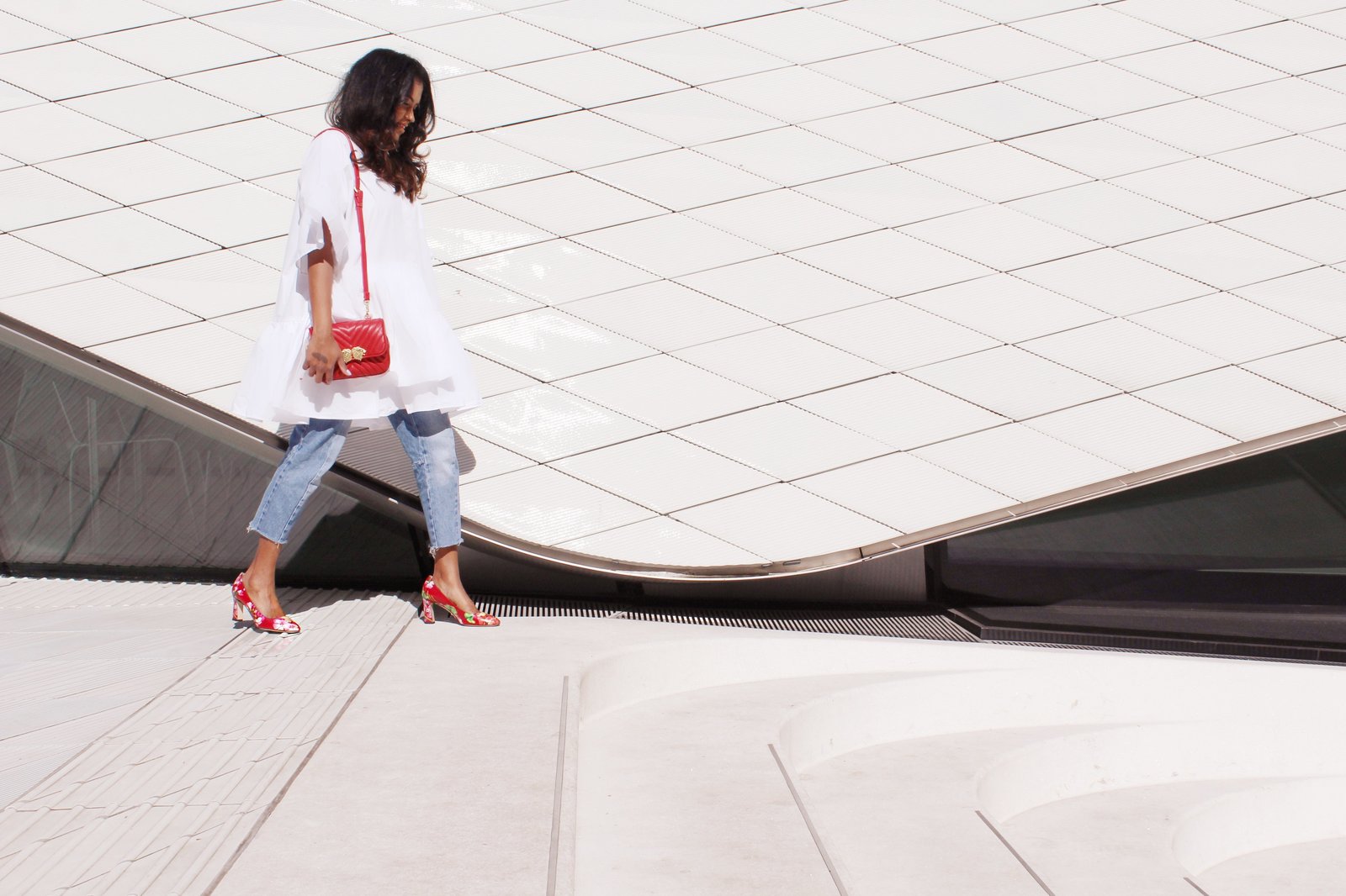 Sachini wearing a white dress, red Gucci shoes and Levi's jeans