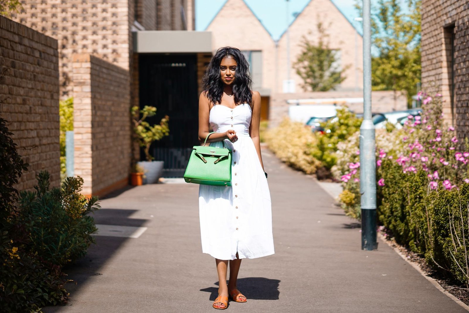 Sachini wearing a white dress holding green bag