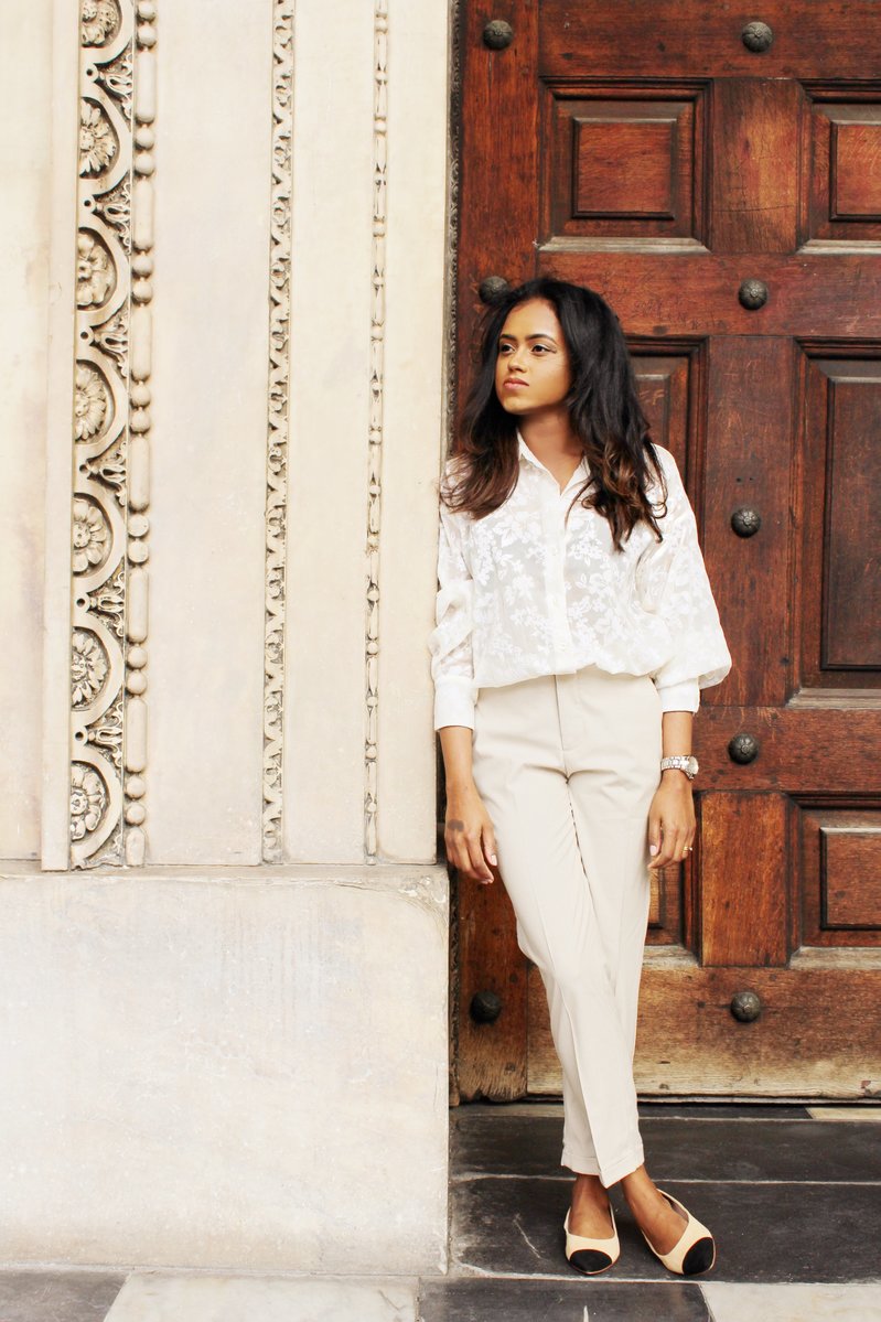 Close up of Sachini wearing a white top and beige trousers 