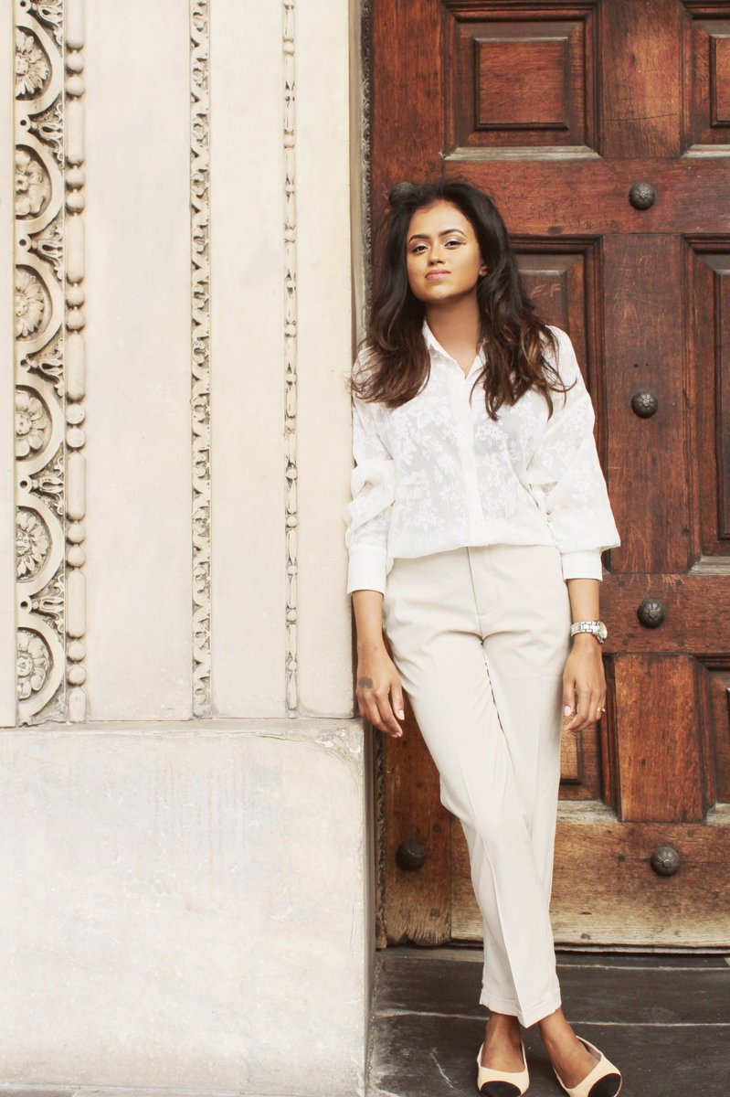 Close up of Sachini wearing a white top and beige trousers 