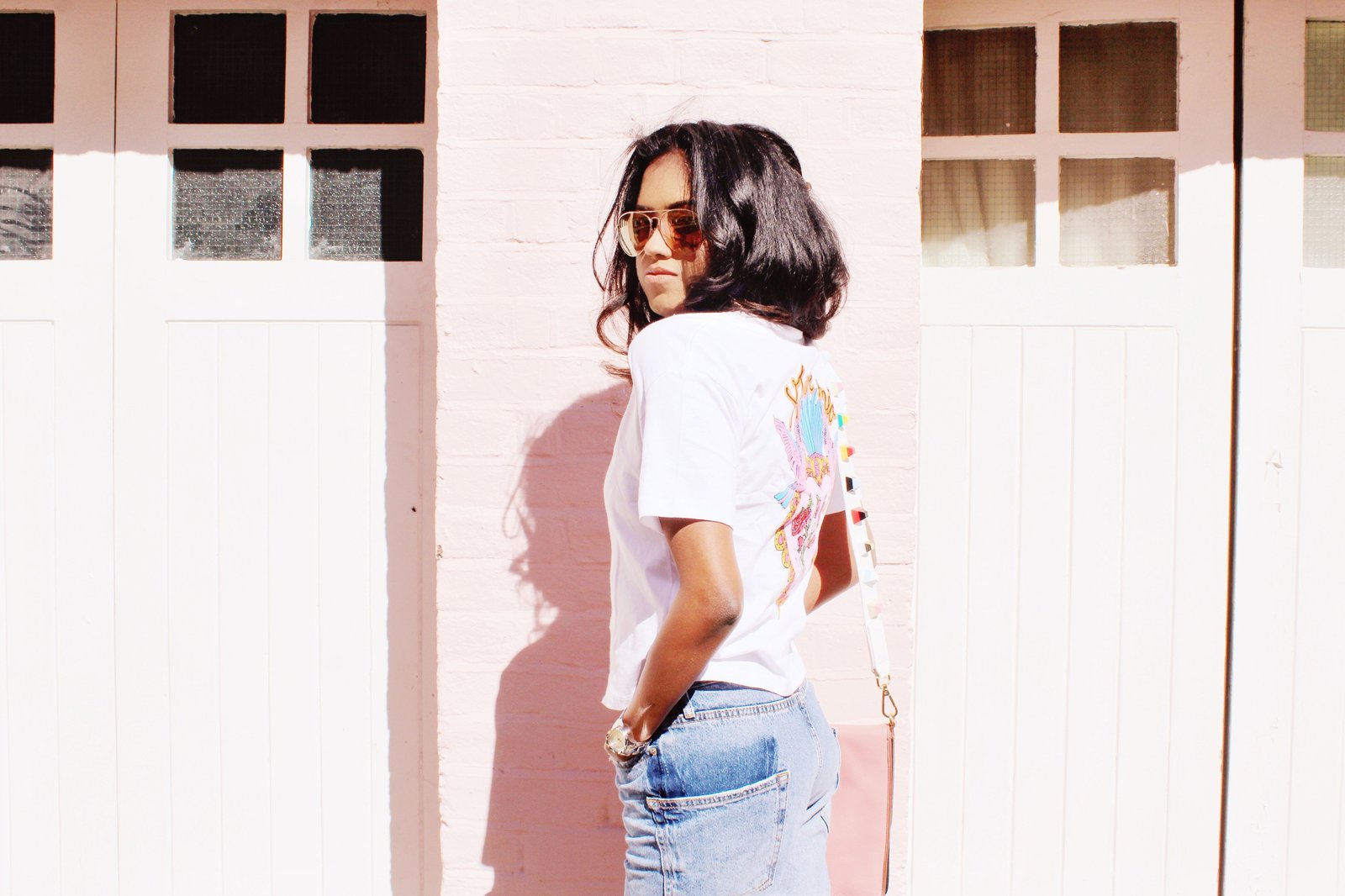 Side view of Sachini wearing a white t-shirt, blue jeans with a pink Dolce and Gabanna