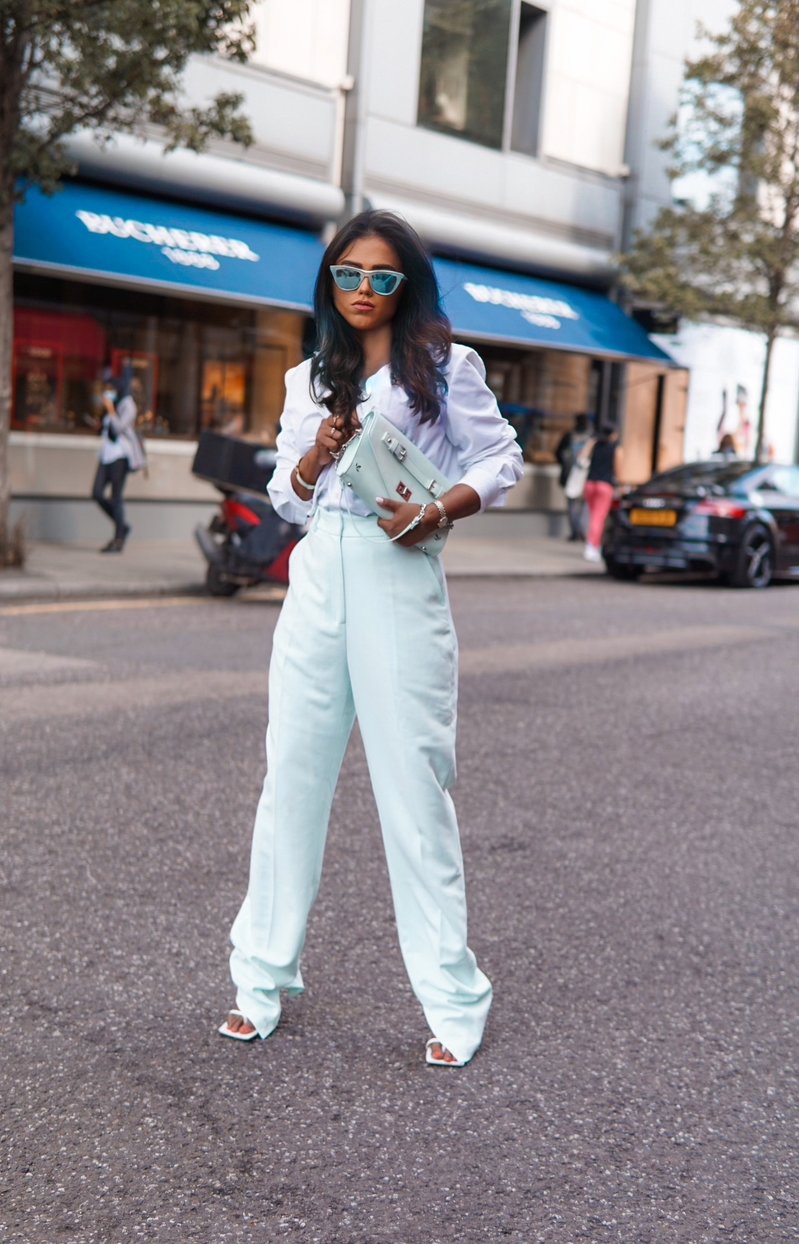 Sachini standing in the streets wearing white Bottega shoes, white top and bottom and a white Ecosusi bag