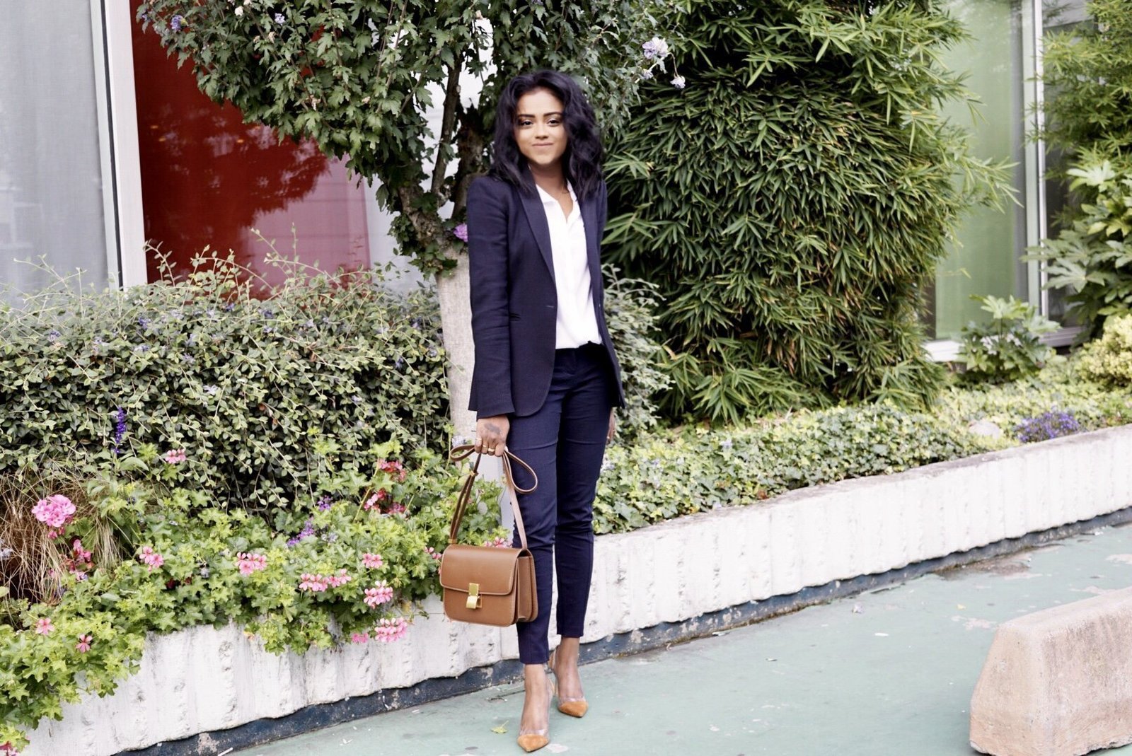 Sachini wearing a black suit and black holding a brown Celine bag