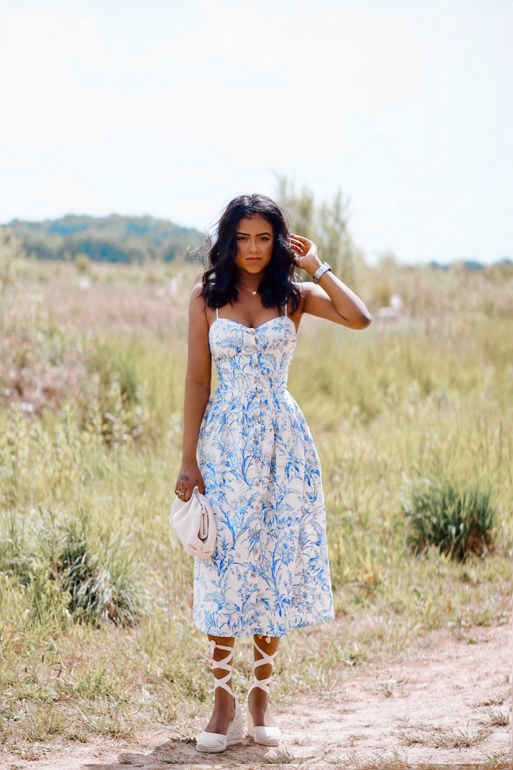 Sachini wearing a white and blue dress in a field 