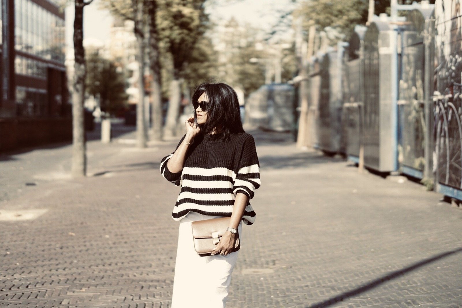 Sachini wearing black and white knitwear, white culottes holding a brown Celine bag