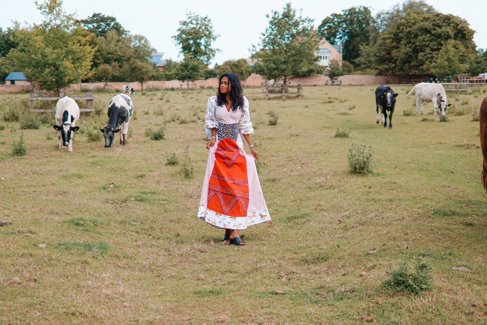 Sachini wearing a Ganni dress with cows in the background