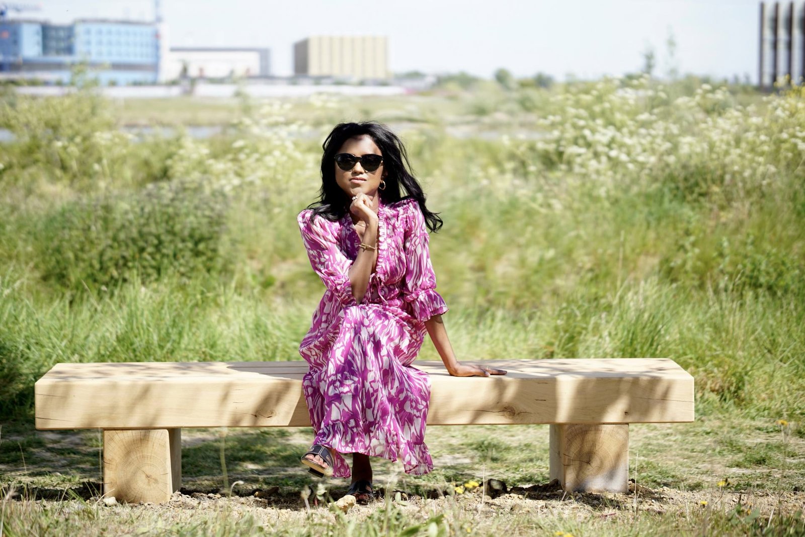 Sachini sitting outdoor wearing a white and pink River Island midi dress