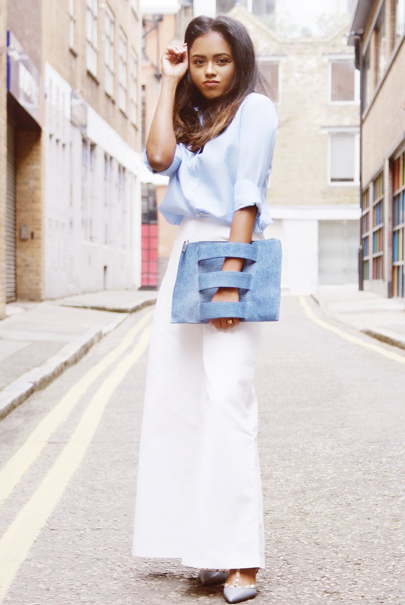 Sachini wearing a blue top, Valentino shoes and white trousers holding a jean colour Embellished Truth bag