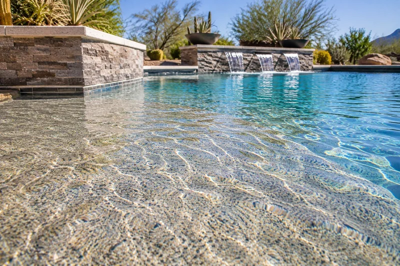 Pebble-finished pool floor and waterfall wall in clear water