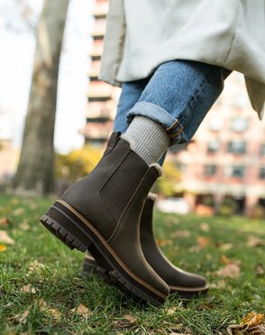 Content creator wearing boots, walking on grass.
