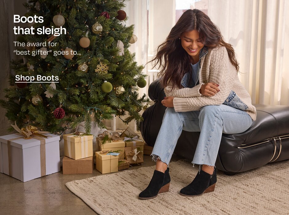 Boots that sleigh. The award for 
“best gifter” goes to… Shop Boots. Model in boots sitting next to Christmas tree and gifts.