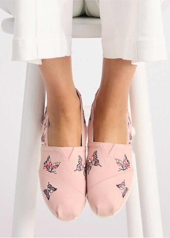 Model wearing Alpargata Classic in pale rose canvas with embroidered butterflies shown.