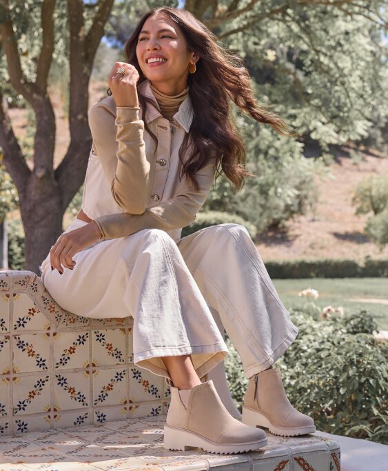 Model wearing Maude Wedge Boot in oatmeal suede shown.