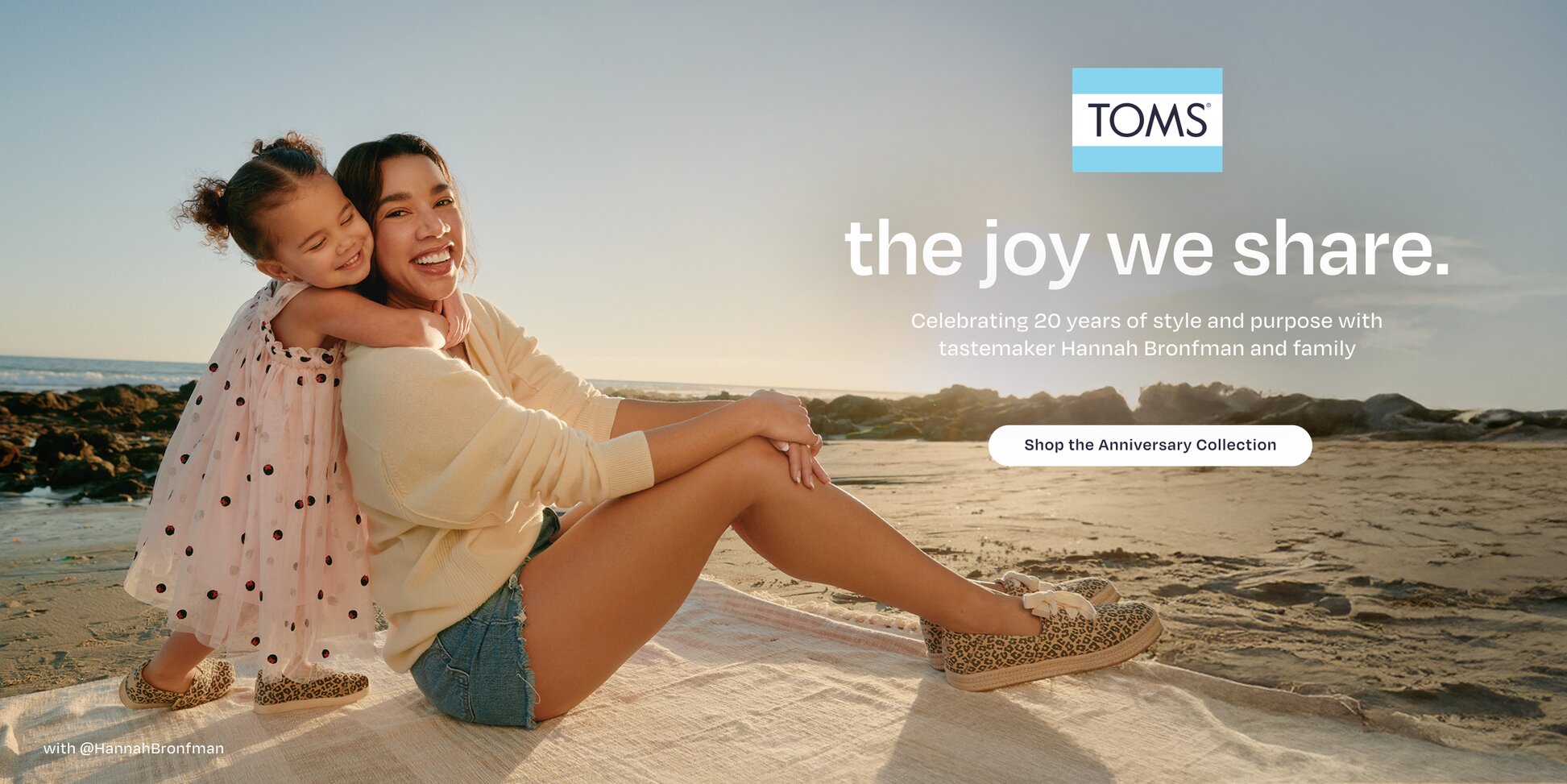 TOMS logo. the joy we share. Celebrating 20 years of style and purpose with tastemaker Hannah Bronfman and family. Shop the Anniversary Collection. Caption: with @HannahBronfman. Daughter hugging Hannah. Beach background.