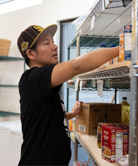 A TOMS employee organizing canned goods shown.