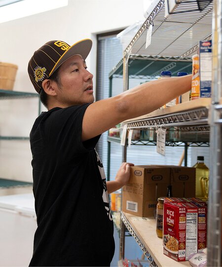 A TOMS employee organizing canned goods shown.
