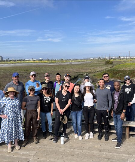 A group picture of TOMS employees after a wetland clean-up shown.