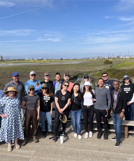 A group picture of TOMS employees after a wetland clean-up shown.