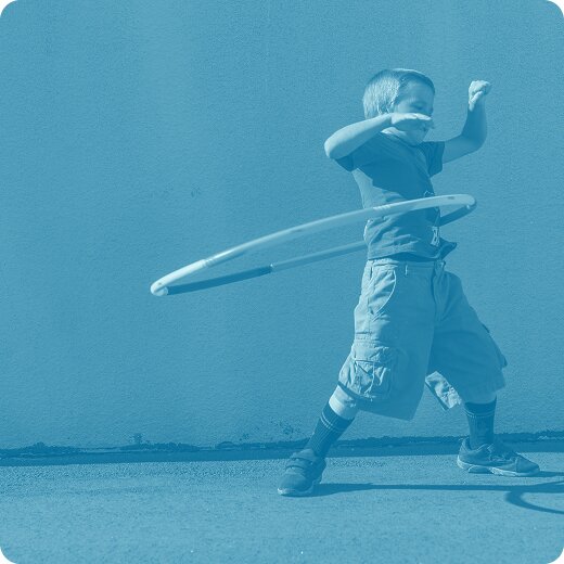 A kid hula-hooping in the playground.
