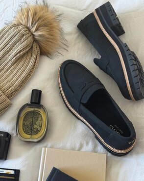 Laydown of loafers, beanie hat, fragrance bottle, and books.