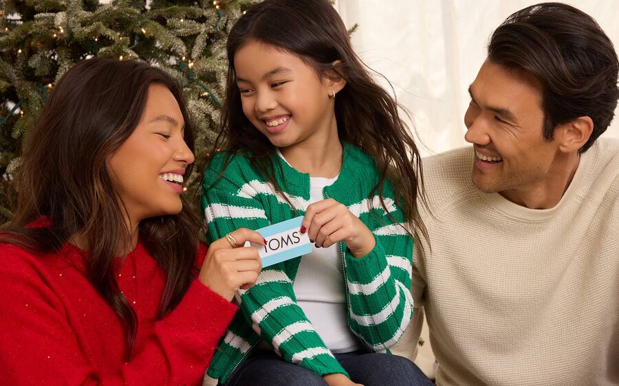 A family holding a TOMS gift card shown.
