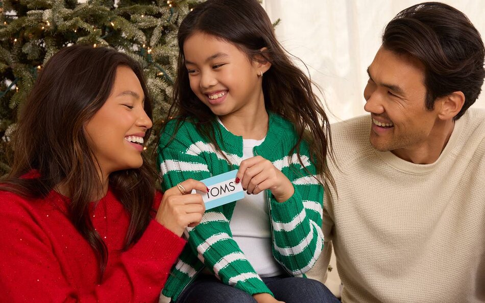 A family holding a TOMS gift card shown.