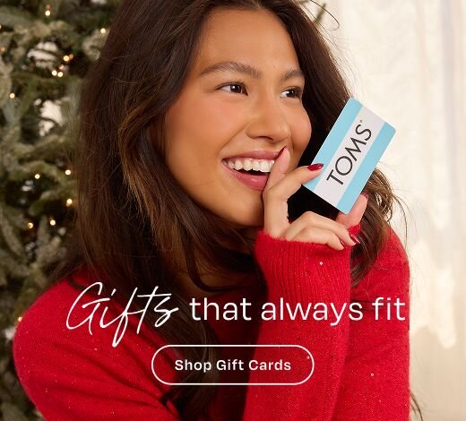 Gifts that always fit. Shop Gift Cards Model holding TOMS gift card.