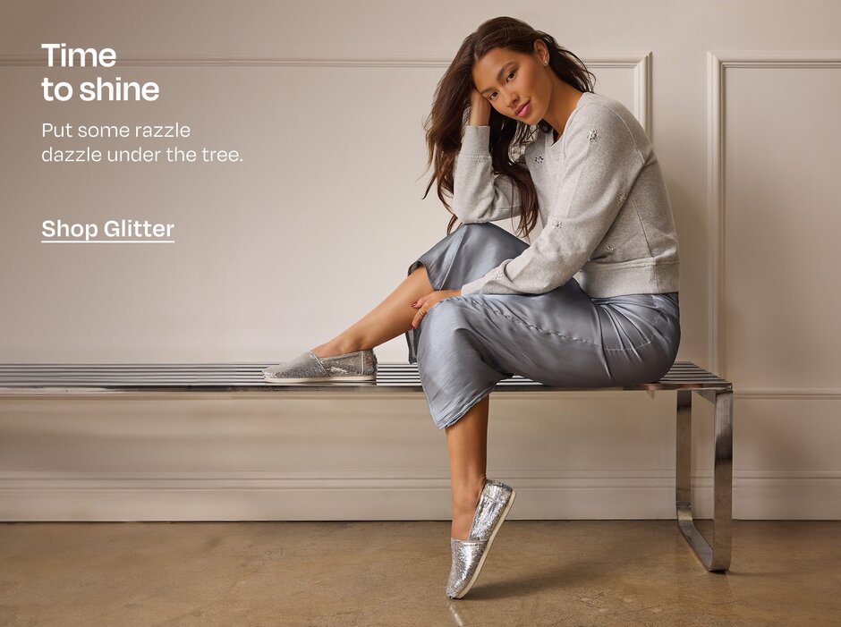 Time to shine. Put some razzle dazzle under the tree. Shop Glitter. Model in sequined Alpargata sitting on bench.