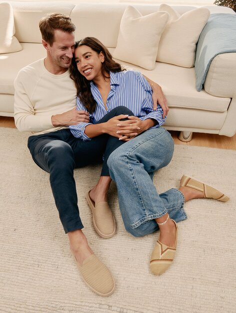 Hannah & husband sitting together, wearing Oat Engineered Mesh Santiago Mule​ & Almond Multi Engineered Crochet Alp​argata.