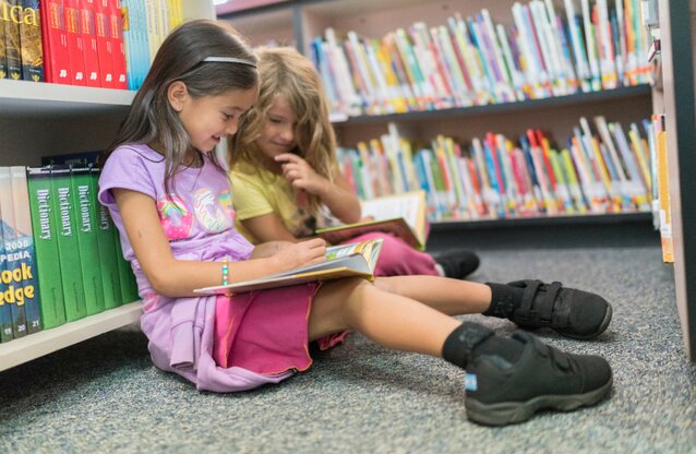 Children reading books at a library.