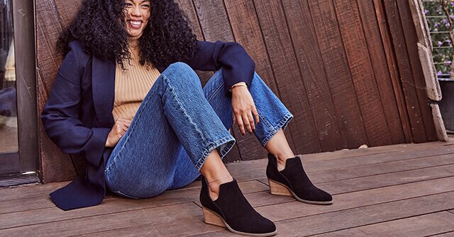 Model wearing the Gwen Ankle Boot in black suede with jeans shown.