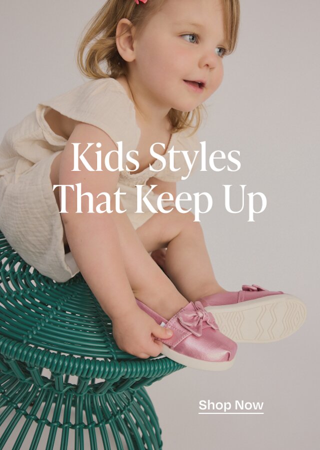 Kids Styles That Keep Up. Shop Now. Model wearing Alpargata Classic Kids Shoe in rose pink metallic twill with bow shown.