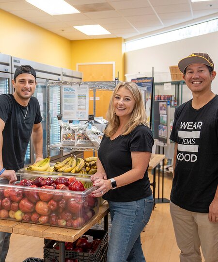 A group picture of TOMS employees in a soup kitchen shown.