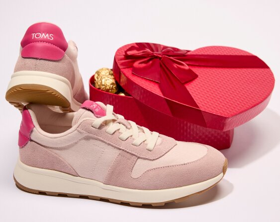 TRVL LITE Retro Runner Sneaker in Water Repellent Pale Rose next to a heart-shaped box of chocolates.
