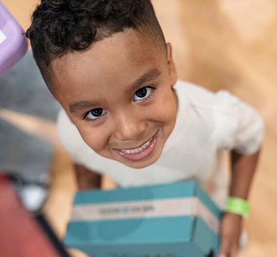 Child holding TOMS shoe box.