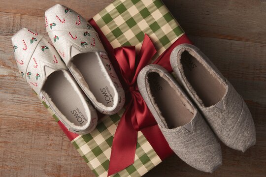 Cozy silver shimmer embroidered candy cane Alpargatas and grey herringbone Alpargatas on a gift box.