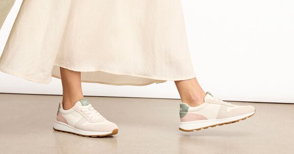 Model wearing the water-repellent TRVL LITE Retro Runner Sneaker in natural egret shown.