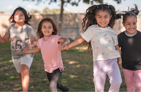 Children holding hands and smiling.