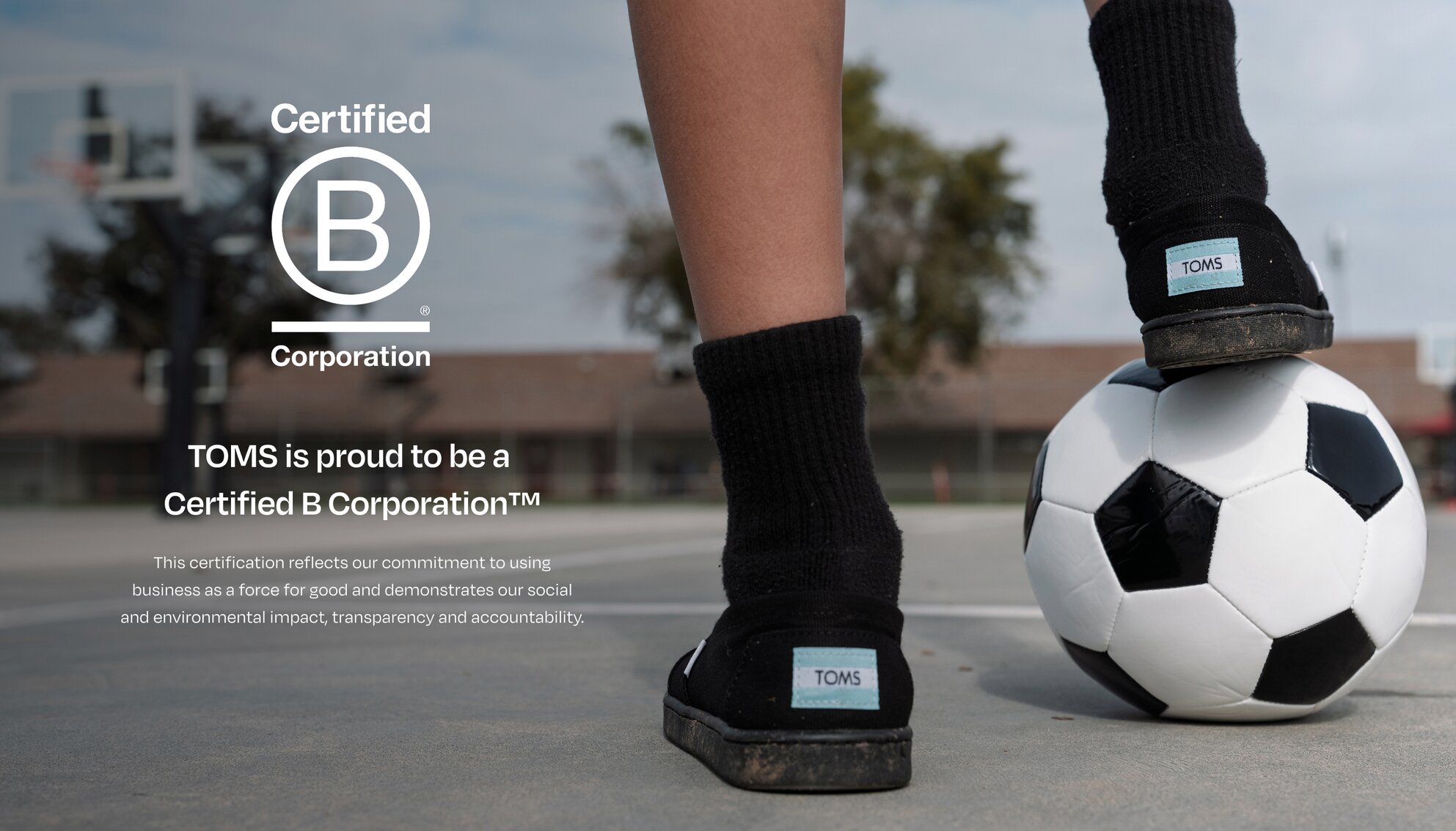 Bcorp logo. TOMS is proud to be a  Certified B Corporation™. This certification reflects our commitment to using business as a force for good and demonstrates our social and environmental impact, transparency and accountability. Child resting foot on soccer ball.