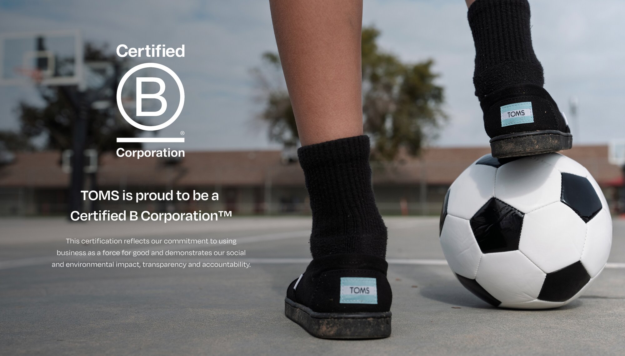 Bcorp logo. TOMS is proud to be a  Certified B Corporation™. This certification reflects our commitment to using business as a force for good and demonstrates our social and environmental impact, transparency and accountability. Child resting foot on soccer ball.