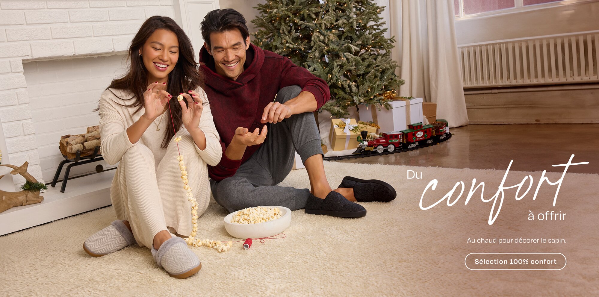 Du confort en boîte Au chaud pour décorer le sapin Collection Cozy Mannequin en chaussons sur le tapis faisant une guirlande de pop-corn.