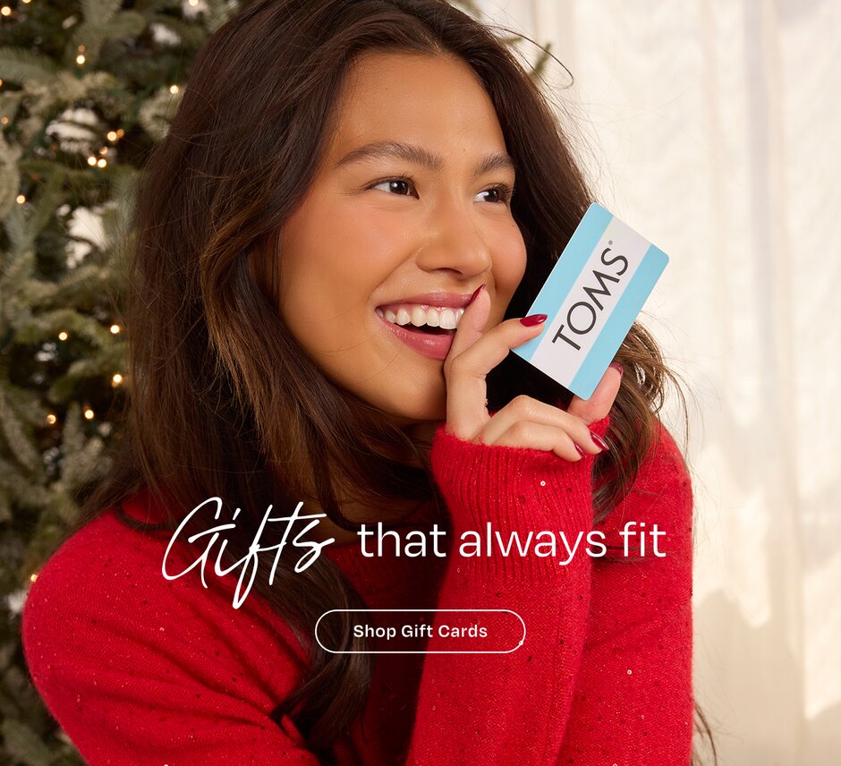 Gifts that always fit. Shop Gift Cards. Model holding TOMS gift card.
