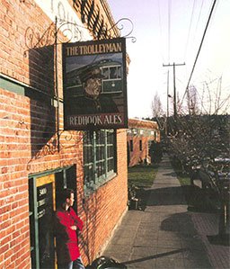 Man in red shirt is standing under Redhooks Trolleyman sign in Fremont. 