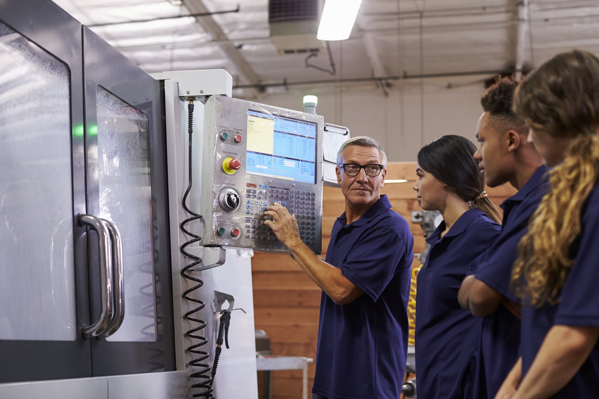 An instructor in front of a CNC machine teaching students