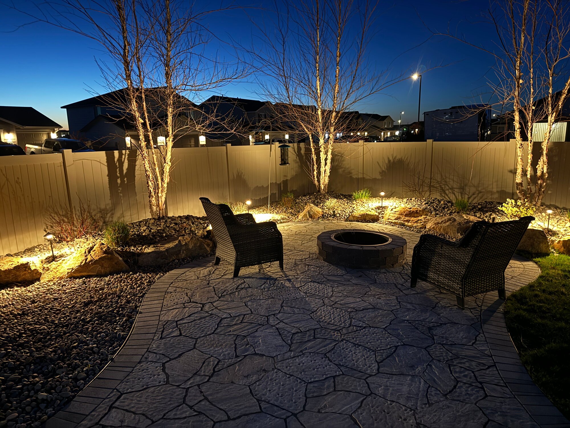 Backyard patio lit up at night with firepit