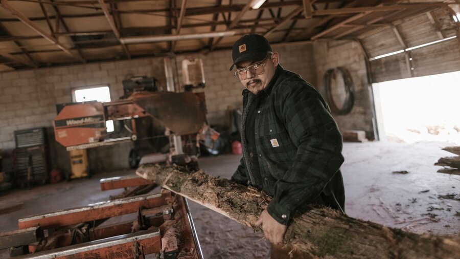 A man in his winter coat with other winter accessories working in his barn.