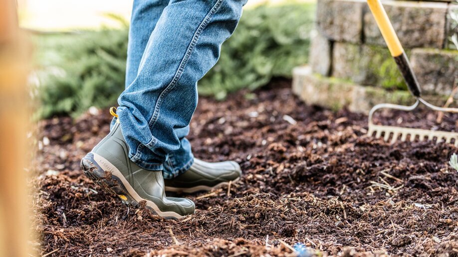 A person wearing waterproof boots to do some yardwork.