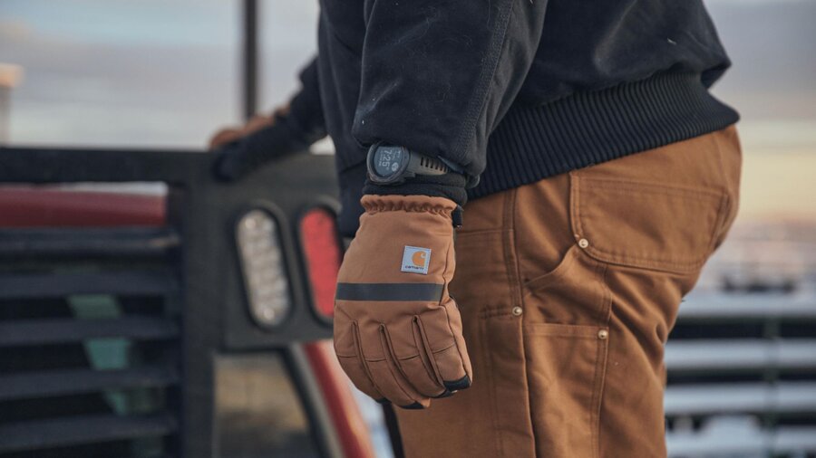 A man working outside wearing winter clothing and gloves.