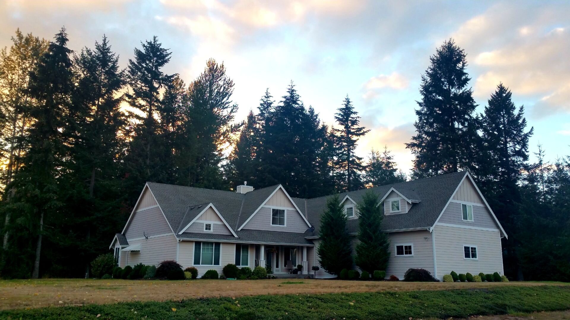 A grand home in Oregon against a backdrop of trees in the fall.